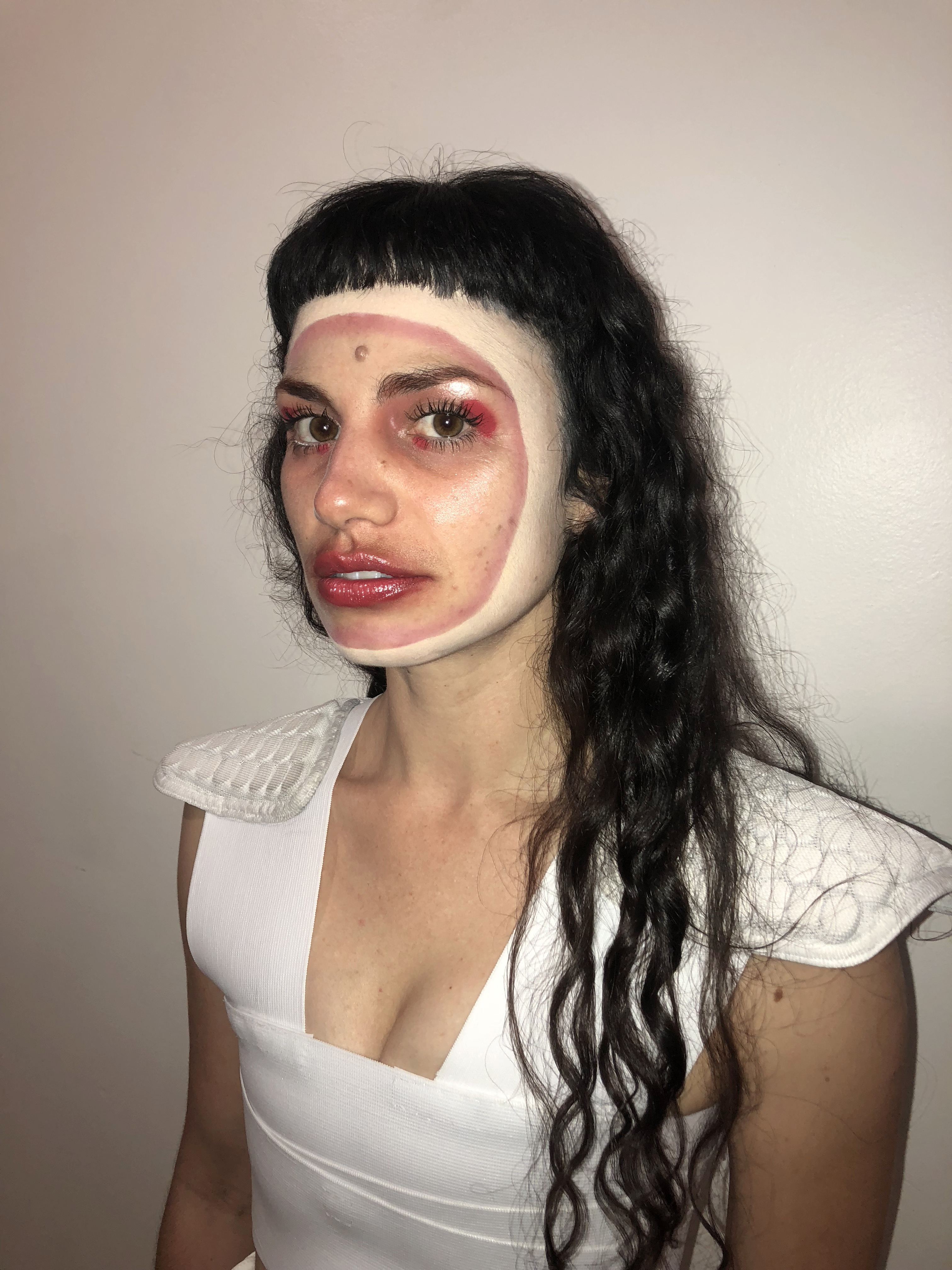 Detail of Alina Bea with neutral and red makeup on with dark hair against a gray background